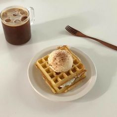 a white plate topped with waffles next to a cup of coffee