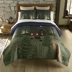 a bed with a quilted cover and pillows on it in front of a stone wall