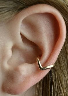 a close up of a person wearing a gold ear cuff