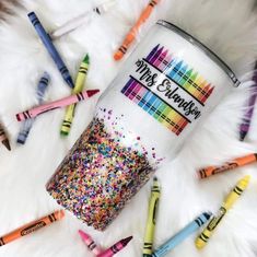 there are many different colored crayons on the white fur and one is holding a cup