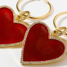 two red heart shaped key chains on a white surface with gold trimmings and diamonds