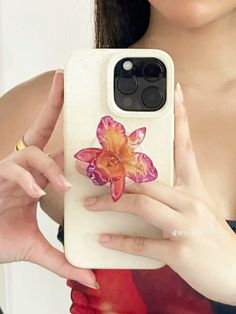 a woman is holding up her phone case with an image of a flower on it