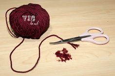 a ball of yarn next to a pair of scissors on a wooden table with crochet needles