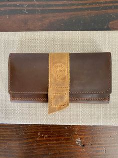 Keep your essentials chic and secure with our Belle Wallet. Crafted from structured brown leather with a light leather contrast, this wallet features a convenient magnetic snap closure and our signature logo stamp. The perfect blend of fashion and functionality! Fits a phone and card slots. 4" x 8" Buda Leather Co products are handmade in Buda, Texas Please note that each piece is one of a kind with natural leather and natural imperfections. Classic Trifold Wallet In Cognac For Everyday Use, Classic Cognac Trifold Wallet For Everyday Use, Classic Cognac Wallets For Travel, Brown Travel Wallet With Coin Pocket, Travel Wallets With Leather Lining In Brown, Cognac Wallets With Card Slots For Travel, Classic Brown Trifold Wallet For Travel, Brown Bifold Wallet For Everyday Use, Travel Wallets In Cognac With Card Slots