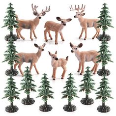 a group of deer figurines standing next to each other in front of trees