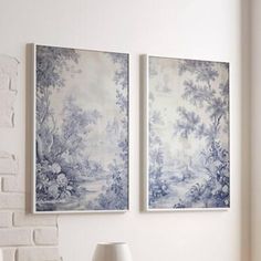 two blue and white paintings hang on the wall above a lamp in a living room