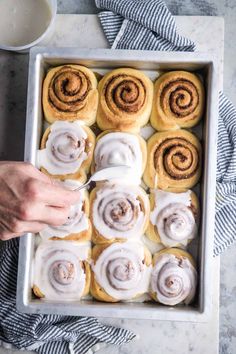 a pan filled with cinnamon rolls next to a cup of coffee