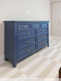 a blue dresser sitting in the corner of a room with checkered flooring and white walls