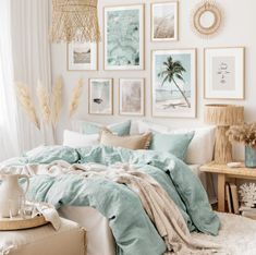 a bedroom with pictures on the wall and a bed covered in blue sheets, blankets and pillows