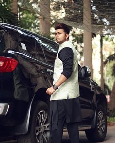 a man standing in front of a black car