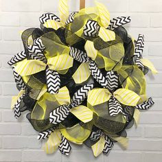 a yellow and black mesh wreath on a white brick wall