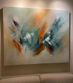 an abstract painting hangs on the wall above a couch