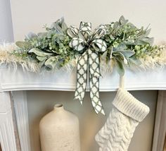 the stockings are hanging on the mantel with greenery and flowers in them, along with a white vase