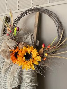 a wreath with sunflowers and leaves hanging on the wall next to a door