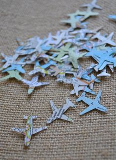 several pieces of paper cut into the shape of airplanes with words on them, sitting on a piece of burlap