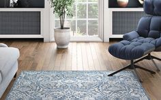 a blue chair sitting in front of a window on top of a hard wood floor