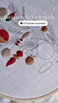 a close up of a cross stitch pattern on a white table cloth with christmas ornaments