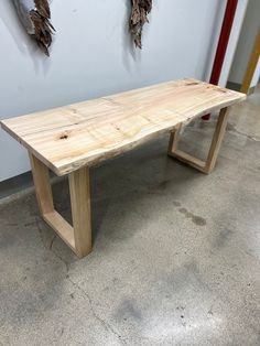 a wooden bench sitting in front of a wall with two hooks on it's side