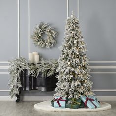 a white christmas tree with presents in front of it and two wreaths on the wall