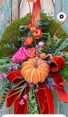 an arrangement of flowers and pumpkins is displayed on a door hanger in front of a wooden wall