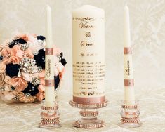 two candles are sitting next to each other on a table with flowers in the background