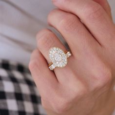 a woman's hand wearing a gold and white ring with an oval shaped diamond