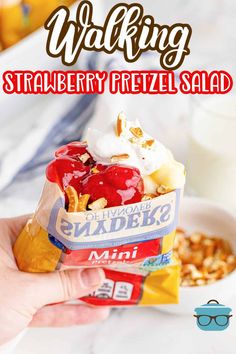 a person holding up a bag of ice cream with fruit and nuts on it, in front of a bowl of cereal