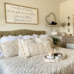 a white bed sitting in a bedroom next to a dresser and mirror on the wall