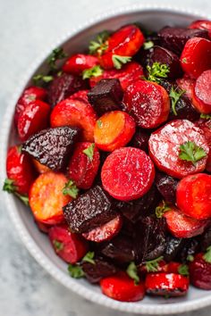 beets and carrots with parsley in a white bowl on a marble surface