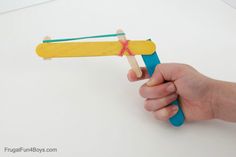 a hand holding a wooden toy airplane on a white surface