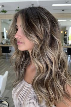 Woman with wavy, layered hair featuring ash blonde highlights and lowlights in a modern salon. Soft Blonde Balayage Brunettes, Light Blonde Highlights In Brown Hair, Dimensional Blonde With Lowlights Fall, Rooty Dimensional Blonde, Blonde With Lots Of Lowlights, Root Melt Dark Blonde, Dimensional Balayage Bronde, Dirty Blonde With Platinum Highlights, Partial Highlights Dark Blonde