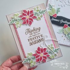 two cards with poinsettis on them being held by someone