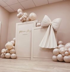 a room with balloons and bows on the wall, along with a white box for an event