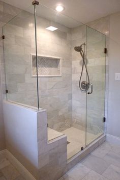 a walk in shower sitting next to a white tiled wall and floor with a glass door