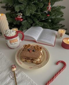 a plate with a sandwich on it next to some candles and a christmas tree in the background