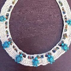 a white crocheted necklace with blue beads and flowers hanging from it's center