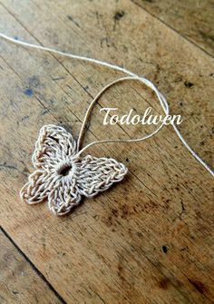 a crocheted butterfly on a wooden floor with the word tadolupn above it