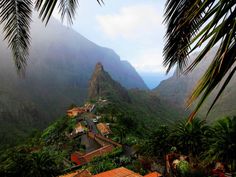 the mountains are covered with trees and houses in the foreground, surrounded by greenery