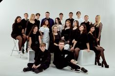 a group of people are posing for a photo in front of a white background with black clothing