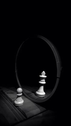 a black and white photo of chess pieces in front of a mirror