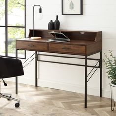 a desk with a laptop on it in front of a window and potted plant