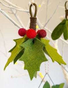 a christmas ornament hanging from a tree with red berries and green leaves on it