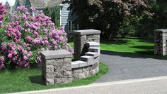 a stone wall and steps in front of some bushes with purple flowers on the other side