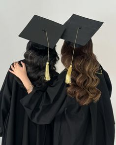 two women in graduation gowns facing each other with their caps and gowns on