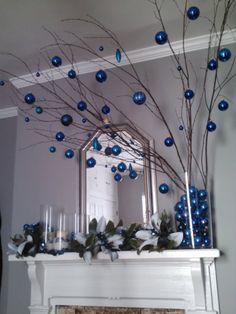 a mantel decorated with blue ornaments and branches