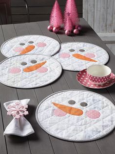 four snowman placemats sitting on top of a wooden table