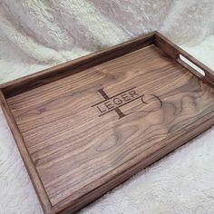 a wooden tray with the word jesus on it sitting on a white blanket next to a cross