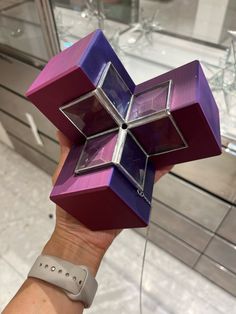 a person holding up a purple and red box