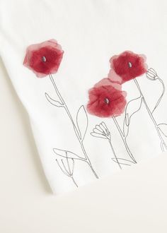 three red flowers on a white shirt with black dots in the center and one flower has been drawn onto it