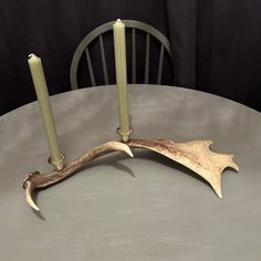 two candles sitting on top of a table next to a wooden antler's head